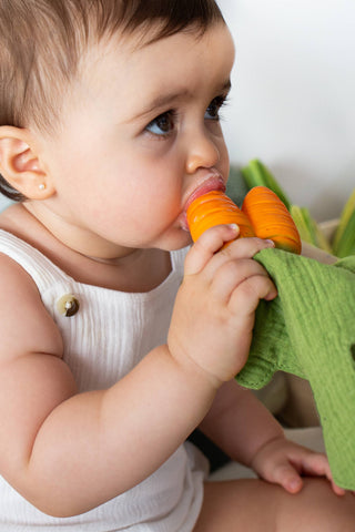 Baby playing with carrot-shaped teether