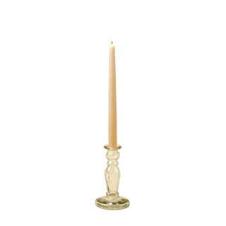 Tall candle in a clear glass holder on a beige background