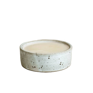 Speckled ceramic bowl with a candle on a beige background