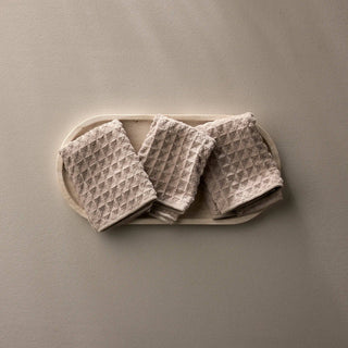 Set of waffle-textured towels on a beige tray against a matching background