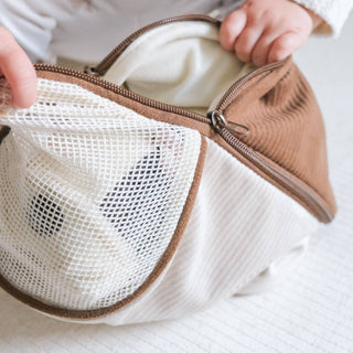 Brown mesh pouch with a zipper held by hands on a light background