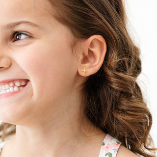 Close-up of a young girl wearing a gold earring with a white background