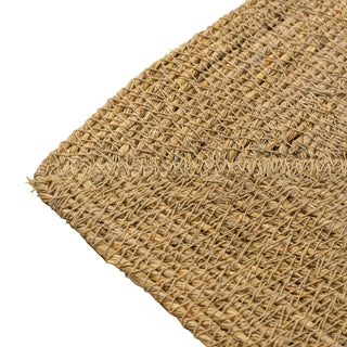 Close-up of a woven natural fiber mat on a beige background
