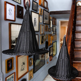 Black woven witch hats hat hanging from ceiling  against a wall with framed pictures