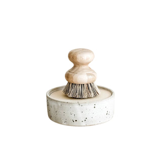 Dish brush with wooden handle and speckled ceramic base on a white background