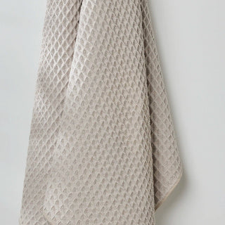 Textured beige towel draped over a white wall