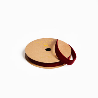 Spool of red ribbon on a cardboard reel with a visible brand logo against a white background