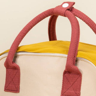 Close-up of a bag with red handles on a beige background