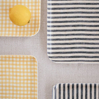 Textile swatch with yellow checkered pattern, lemon, gray and white striped pattern on a neutral background.