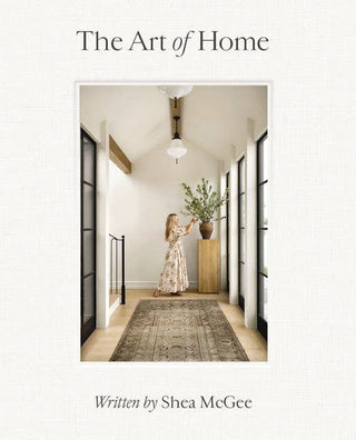 Book cover of 'The Art of Home' by Shea McGee featuring a woman in a hallway.