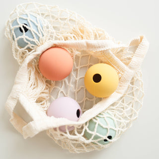 Mesh bag with colorful bath bombs on a light background