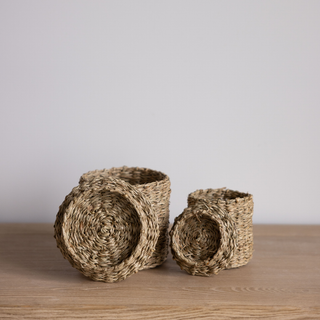 Two woven baskets on a wooden surface with a plain background