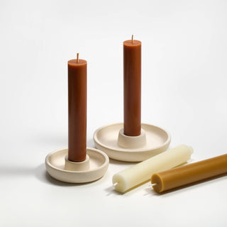 Two brown candles in ceramic holders on a white background