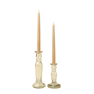 Two glass candlesticks with lit candles on a beige background
