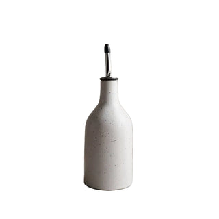 White ceramic bottle with a black cap on a light gray surface and background
