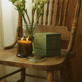 Wooden chair with a candle, books, and flowers on a wooden table.