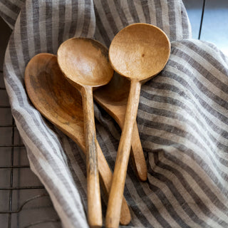 Three wooden spoons on a striped fabric background