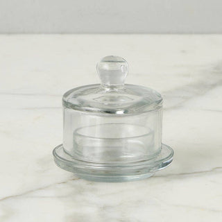 Clear glass butter dish with lid on a marble surface
