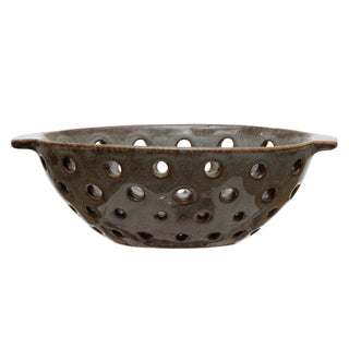Brown ceramic colander with holes on a white background