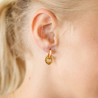 Gold hoop earring worn by a person with blonde hair.
