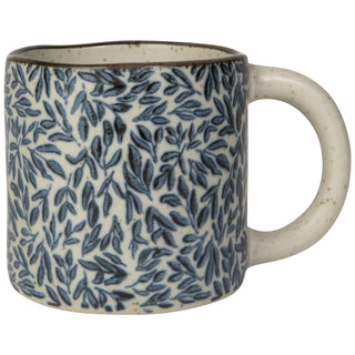 A ceramic mug with a blue leaf pattern on a speckled cream background, featuring a dark brown rim and a matching cream handle.