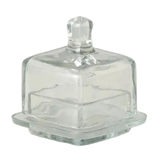 Clear glass butter dish with lid on a white marble surface