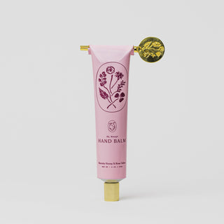 Pink hand balm tube with floral design and gold cap on a white background