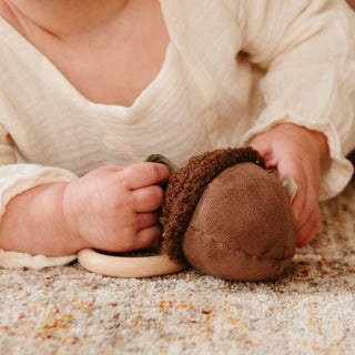 Baby holding a brown plush toy on a carpeted floor