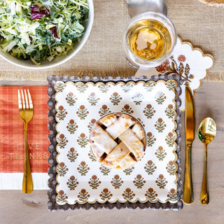 Thanksgiving table setting with salad, pie, and autumn-themed placemat.