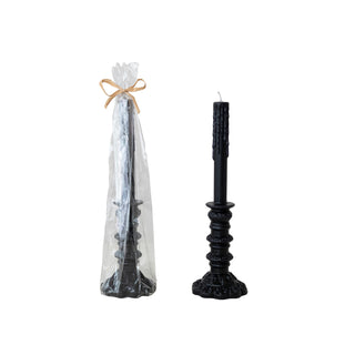 Black candle with decorative base next to a clear cone-shaped packaging on a white background