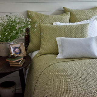 Bed with green bedding and pillows in a bedroom setting