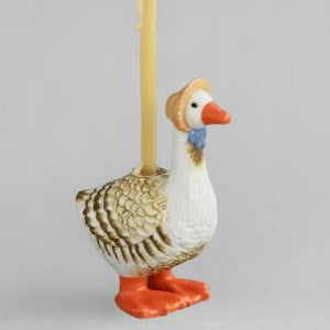Decorative goose-shaped candle holder with a lit candle on a gray background